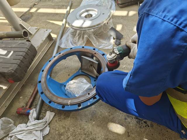 现场人员使用手持工具处理蓝色泵壳结合面