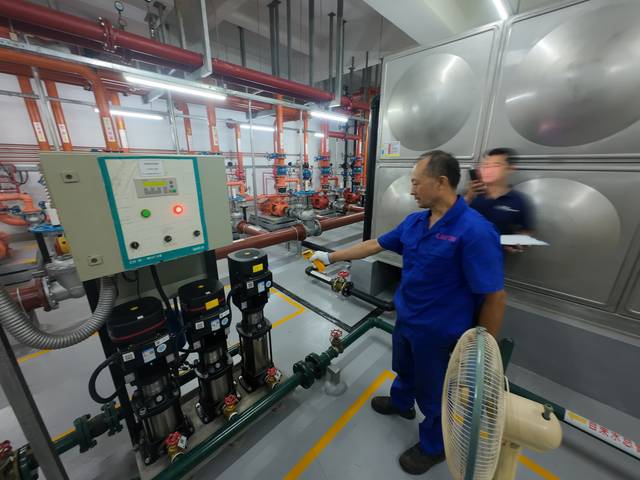工作人员用黄色手持仪器对准立式泵组电机区域